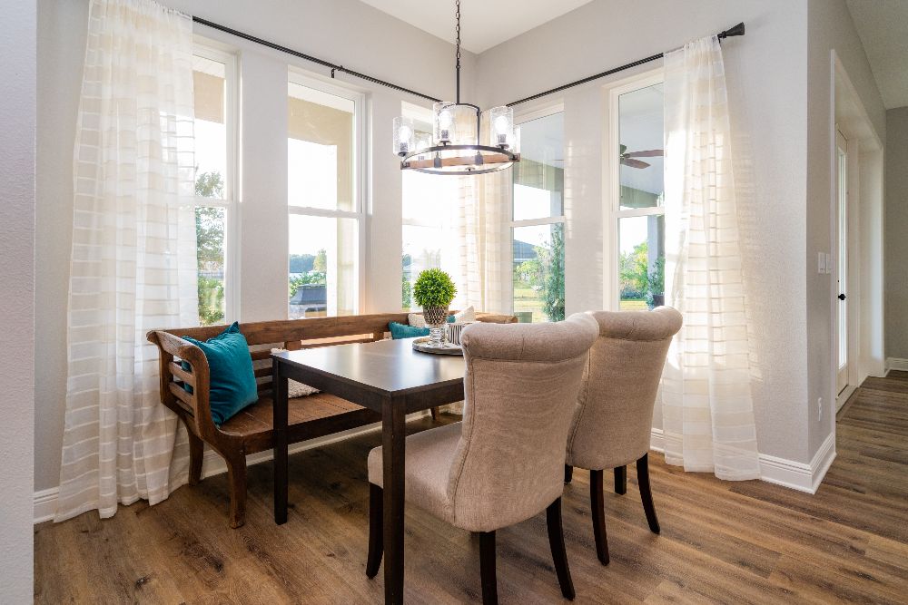 A breakfast nook off the kitchen with a small rectangular table, bench seating on one side and two upholstered chairs on the other.