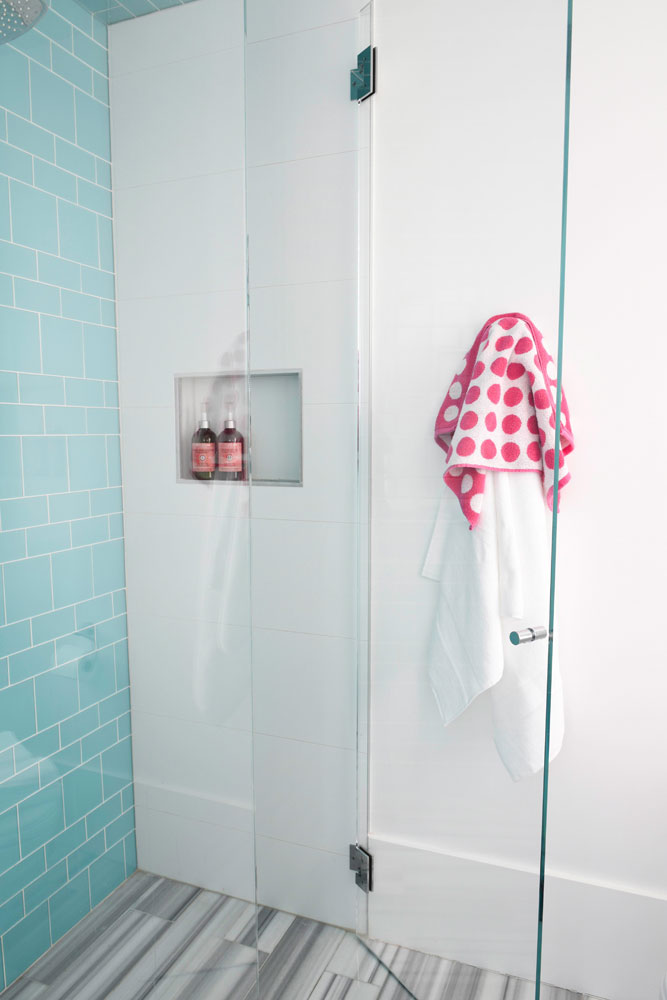 blue subway tile wall in shower with niche and pink and white polka dot towel