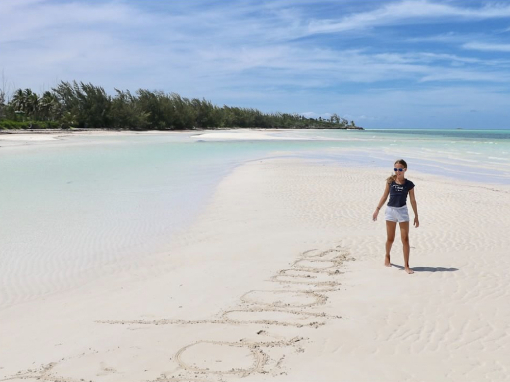 Charlotte Baeumler writes out Bahamas in the white sand