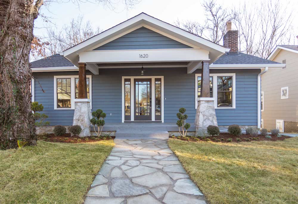 Exterior of a cute blue and white bungalow with a wide flagstone path, lawn and landscaped garden beds as features on Masters of Flip on HGTV Canada