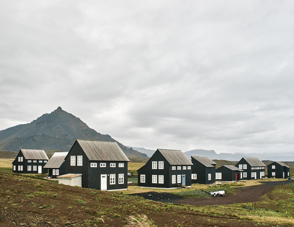 A row of traditional Icelandic homes painted all black with black roofs and white window and doors.