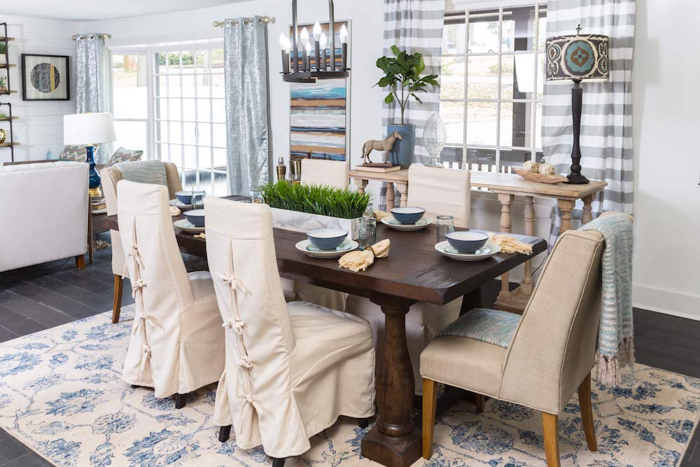 Masters of Flip split level dining room table with white linen covered chairs and blue bowls set on plates and chargers