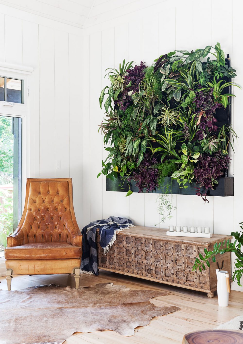 living wall of plants beside tan tufted leather chair
