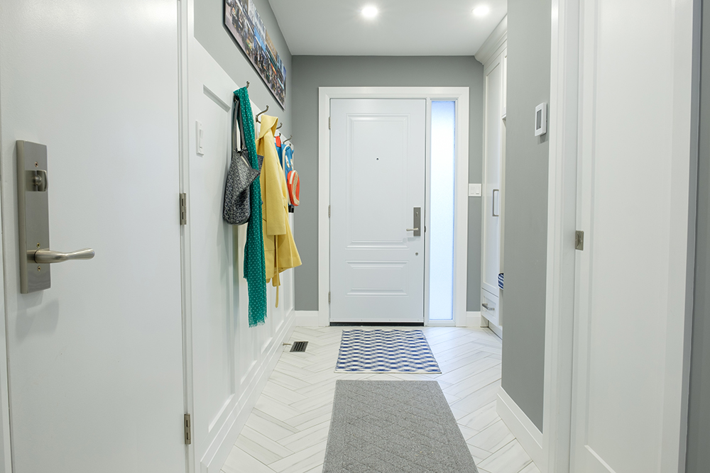 White front hall with herringbone tiles and coats hanging on hooks
