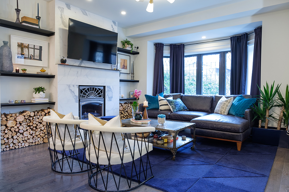 Modern living room with blue area rug, marble faced fireplace and white modern iron chairs