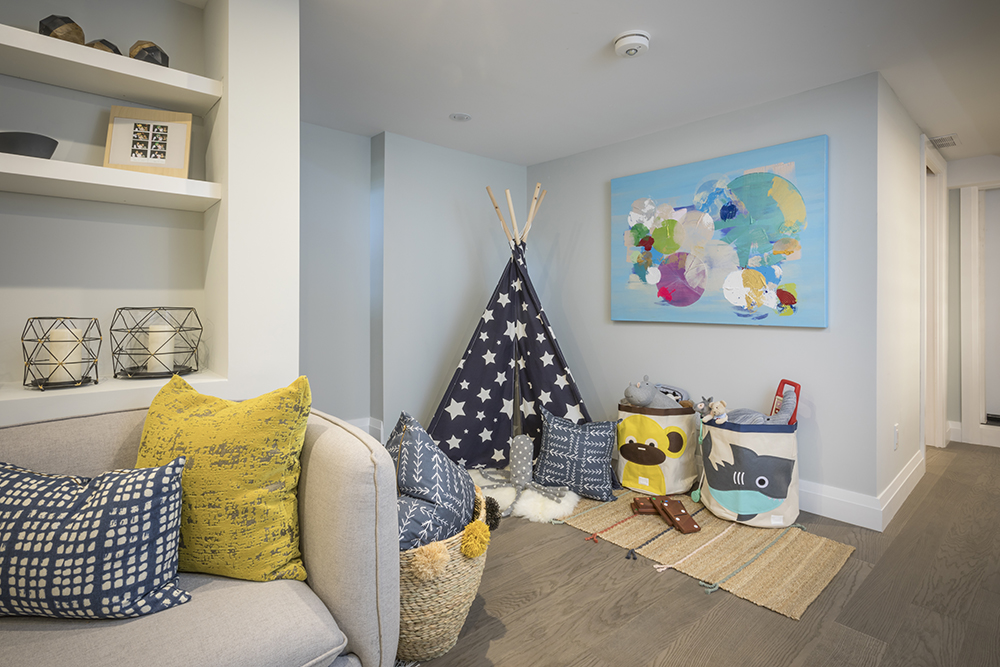 Cute kids play corner with a star covered teepee, two baskets of toys and colourful piece of art on the wall