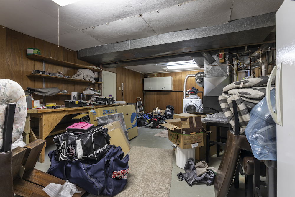 A dirty basement piled high with hockey equipment, boxes and old tools