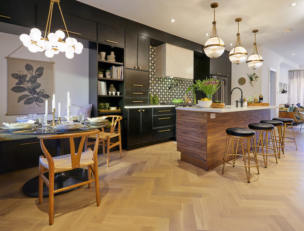 Chic dining nooks sits beside a modern kitchen with black cabinets and a large centre island