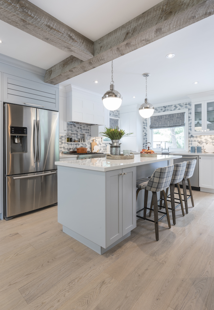 Ice blue kitchen island with quartz countertops, two large silver pendants lights and three plaid covered stools