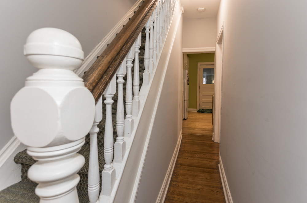 Narrow hallway with a white bannister and old wood floors