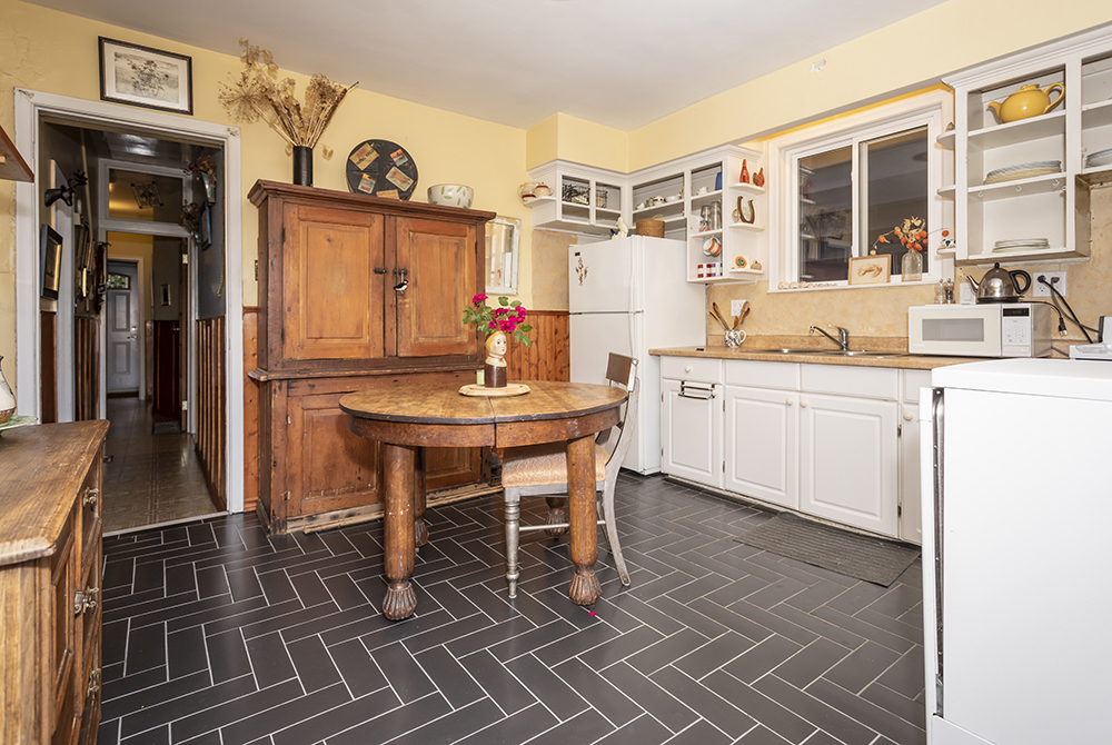 Charming country inspired kitchen with black herringbone tiled floors and a round wooded dining table