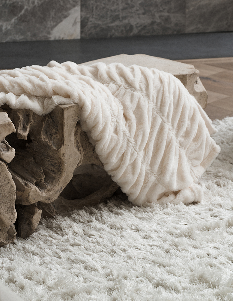 Wooden bench with a thick plush white blanket thrown over it