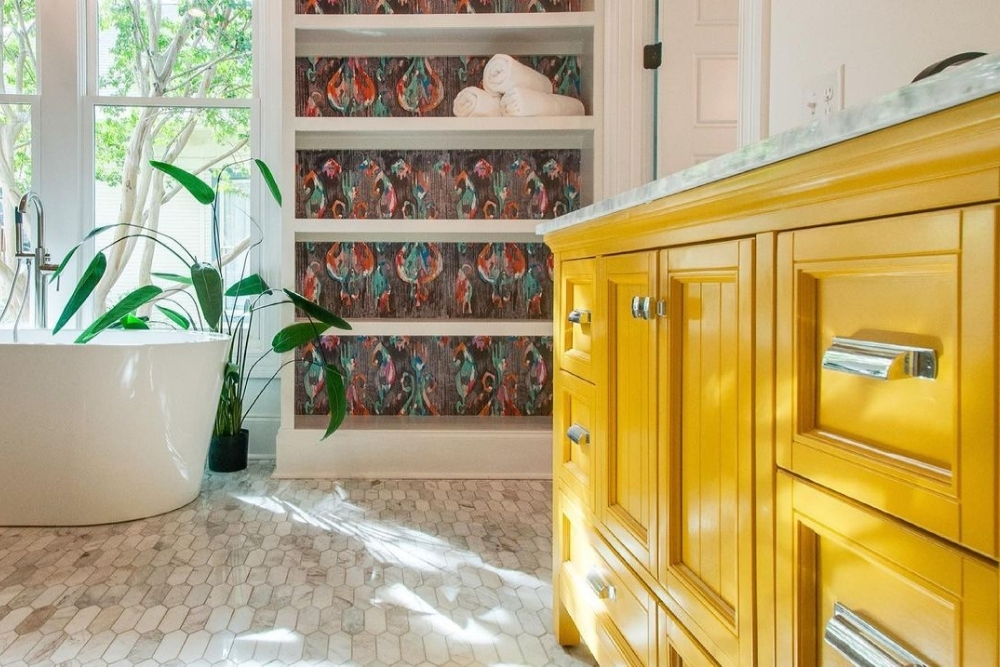 Yellow bathroom cabinet and bookshelf with bold wallpaper print