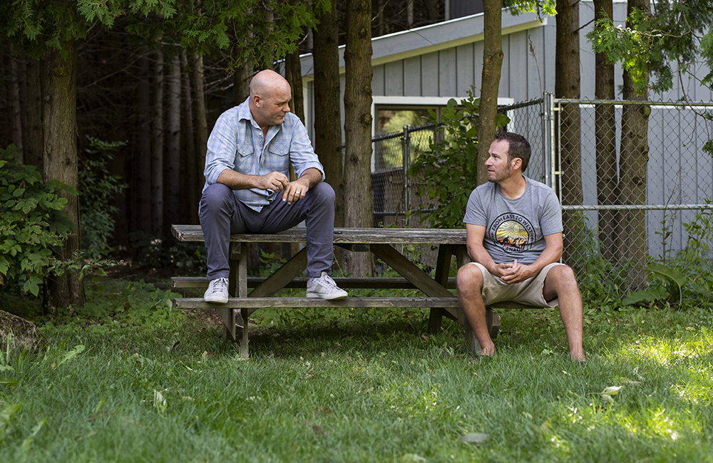 Bryan Baeumler and Adam having a chat on a picnic table in Toronto.