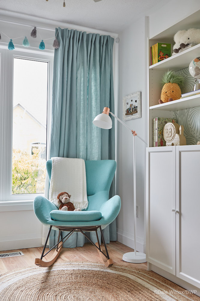 corner of white nursery with blue rocking chair