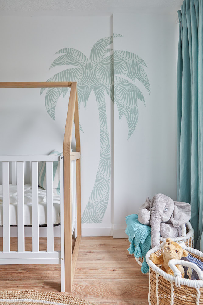 white nursery with crib and green palm tree wall decal