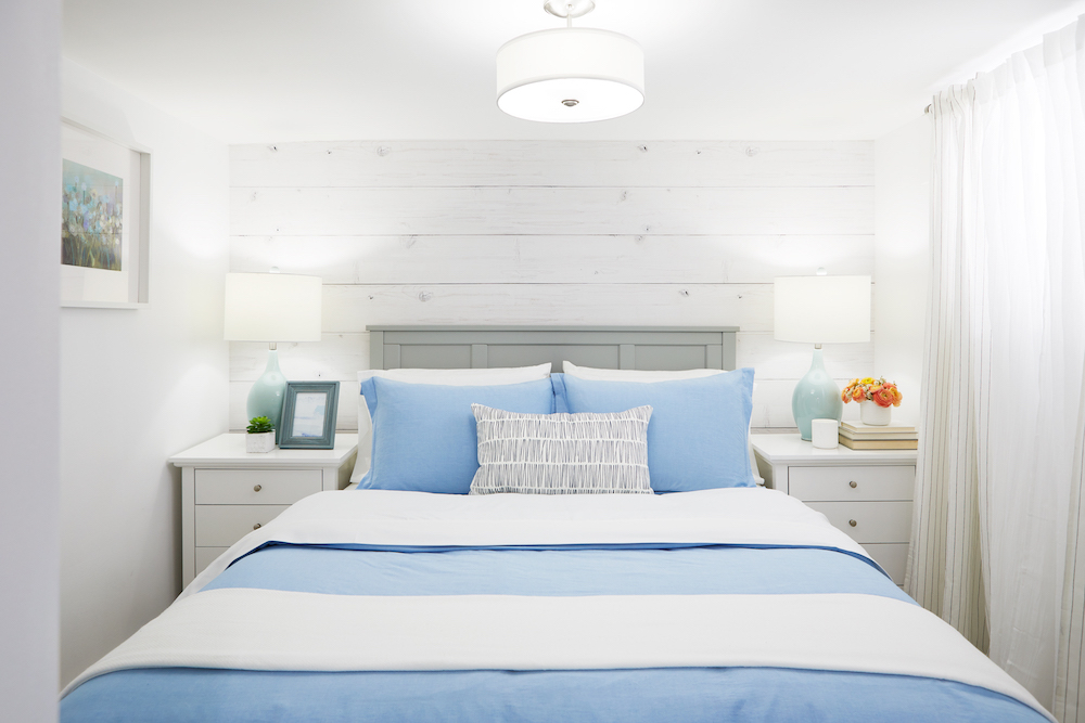bright white bedroom with wood-style feature wall and blue bed