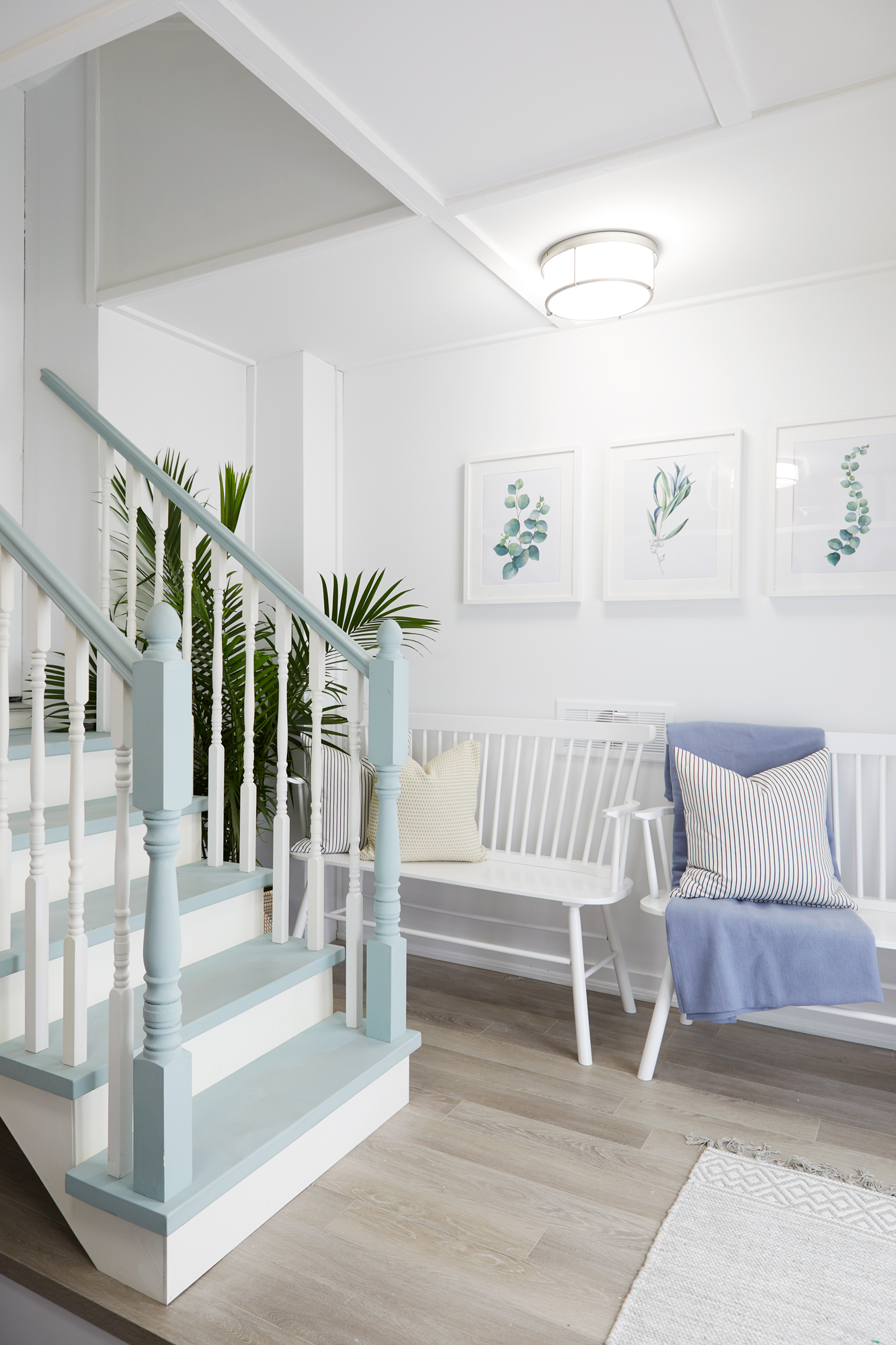 white entryway with blue staircase, brown floors and white bench seating