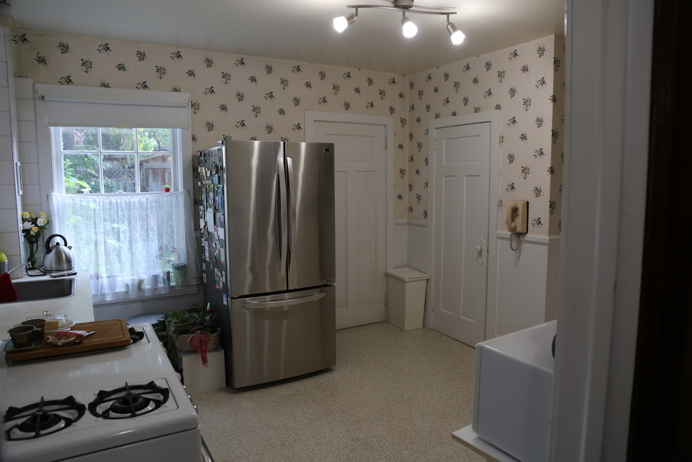 old kitchen with floral wallpaper and stainless steel fridge