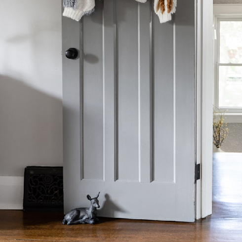 A shot of an open door with a hanging sweater and deer knick knack