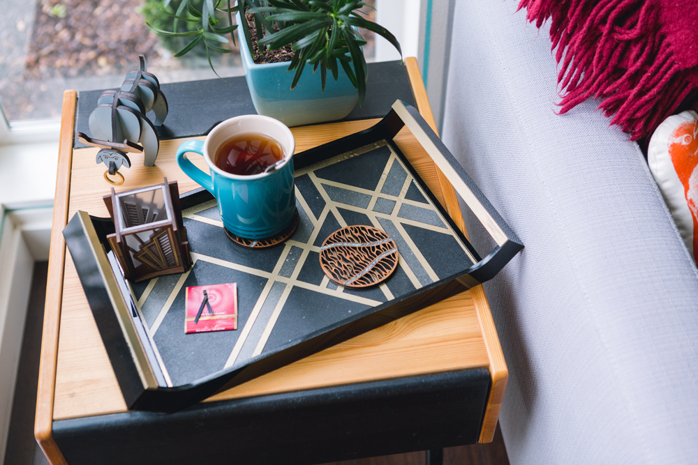 An abstract patterned food tray with a coaster and cup of tea on top