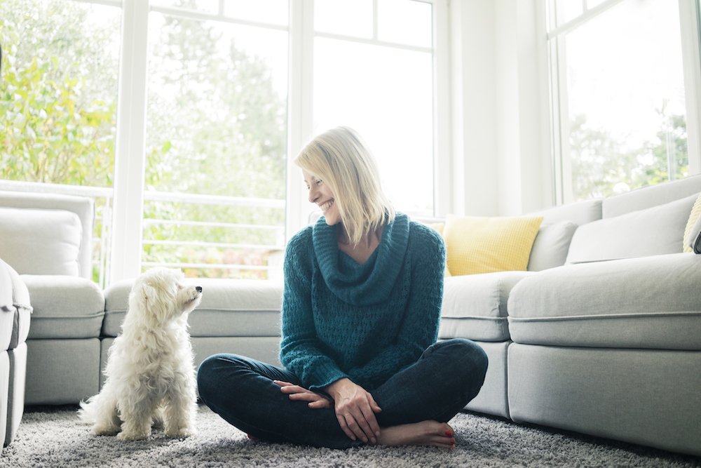 Smiling woman looking at her dog in living room