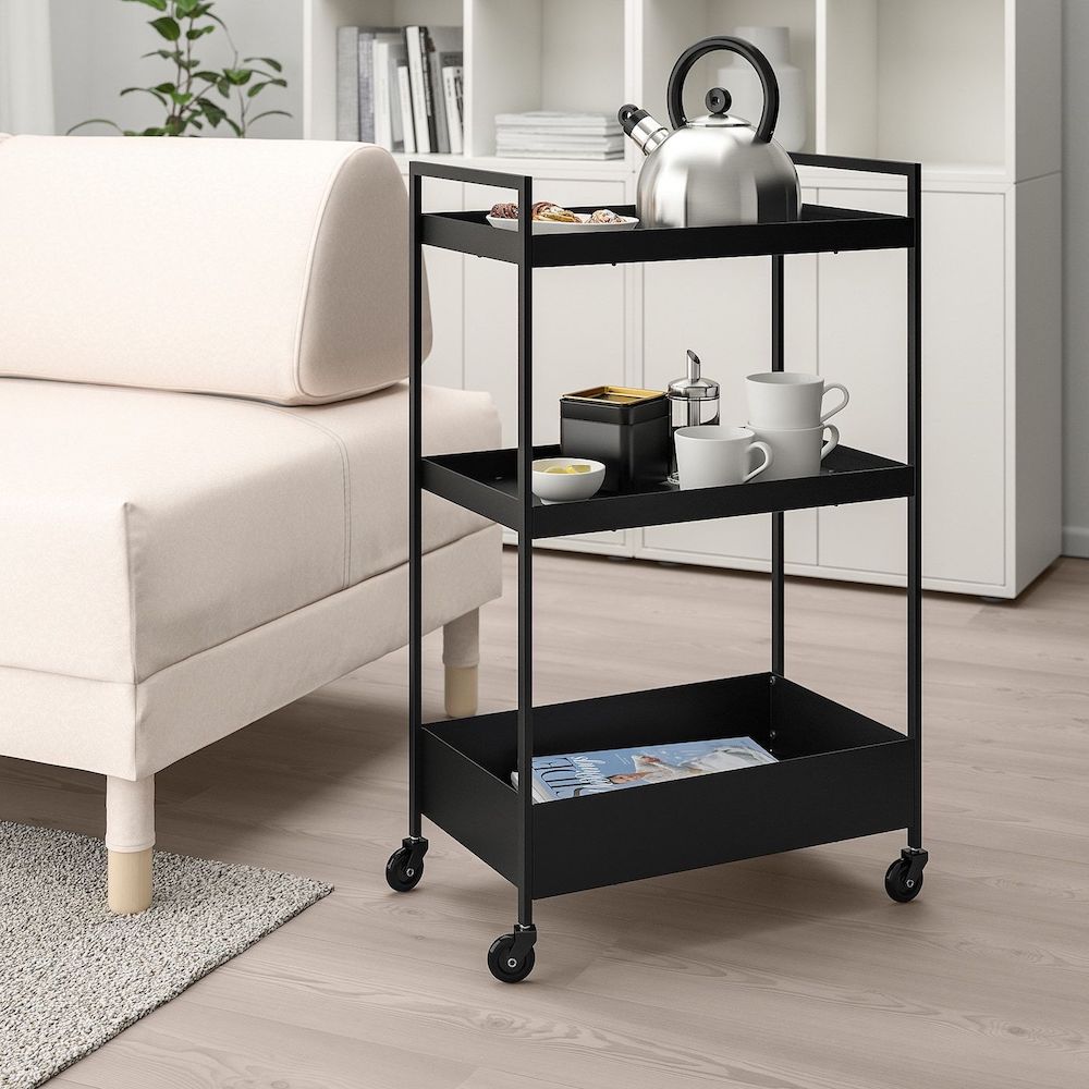 Simple black metal utility cart holding a kettle, cookies, mugs and magazines in a chic modern living room