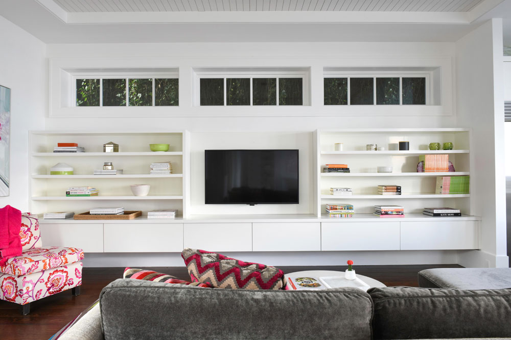 living room wall with tv, white built-ins and shelves and set of three windows above