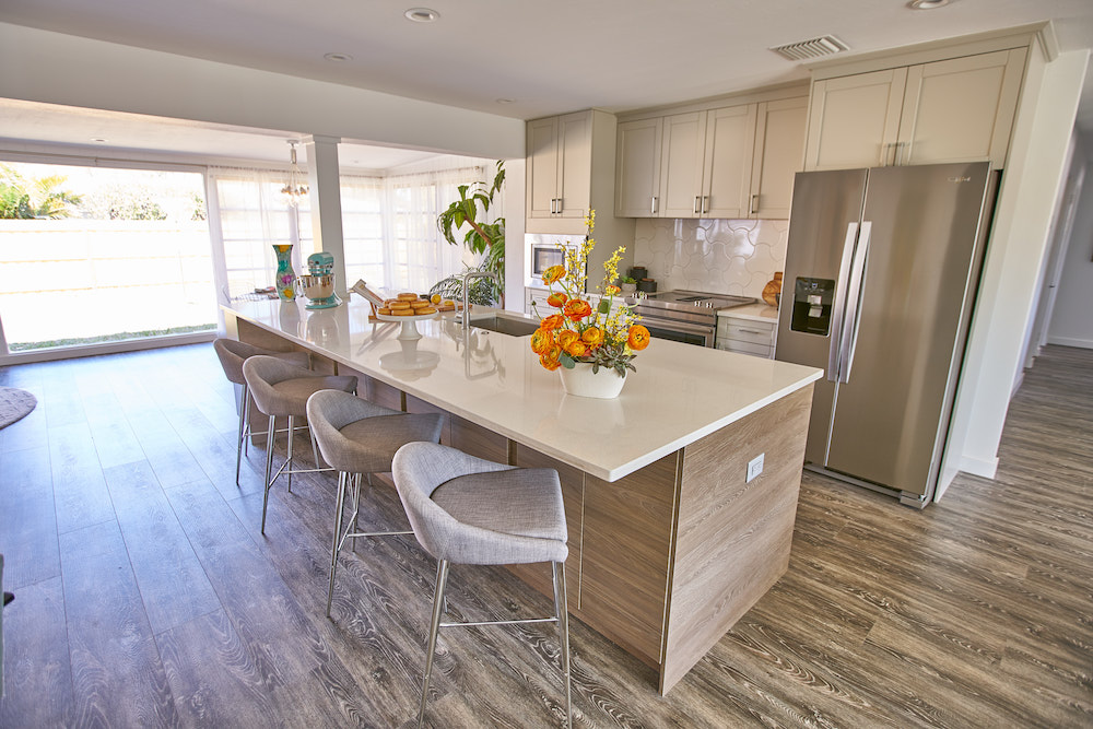 Buyers Bootcamp beach bungalow kitchen with white quartz countertops on a large island and a floral display
