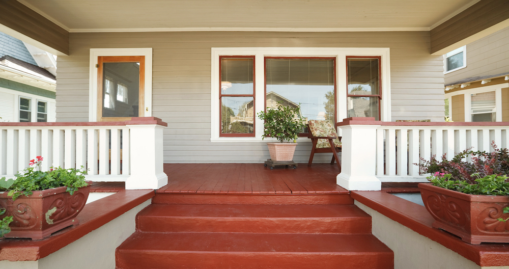 Welcoming front steps of a heritage craftsman house painted in BEHR Aged Beige PPU7-09, with white trim in BEHR Polar Bear 75 and red stairs and trim in red BEHR Fire Cracker PPU2-16