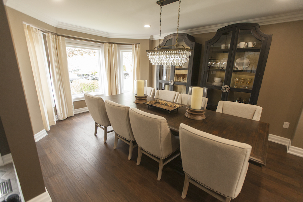 A formal dining room with long wooden table and eight beige upholstered chairs