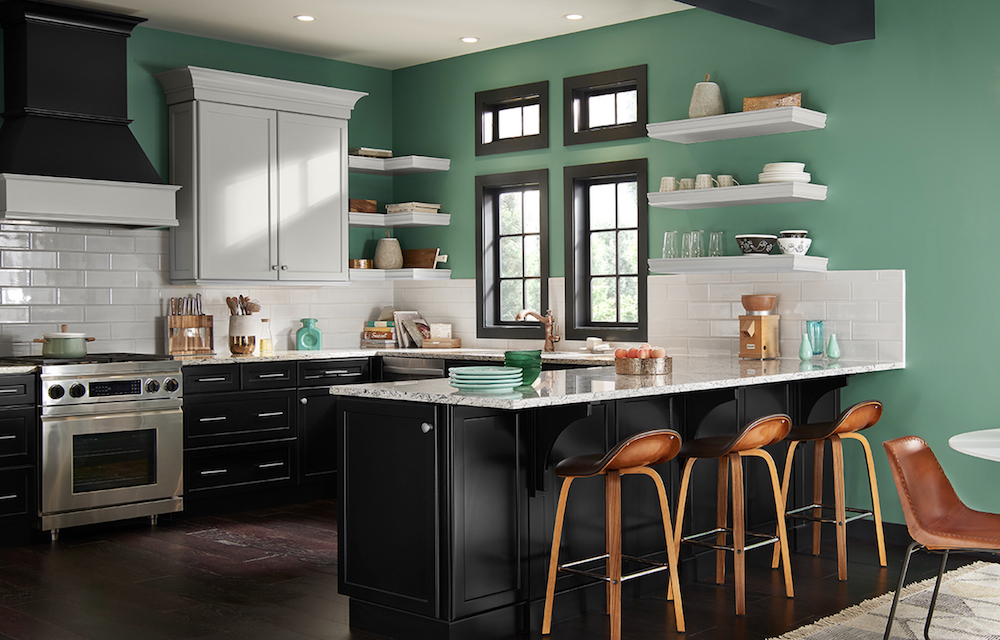 Cool modern kitchen with a quartz topped island, stainless steel appliances, wood floors, black cabinets painted in BEHR Carbon N520-7, green walls in BEHR Free Green M420-5, and open shelves in BEHR Painter's White PPU18-08