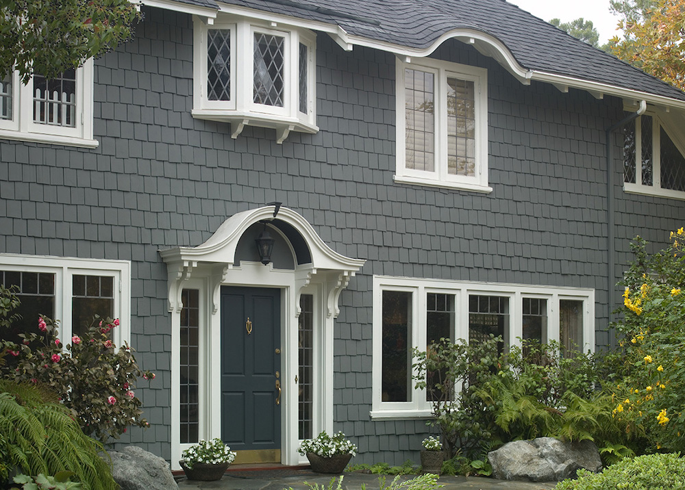 Exterior of a beautiful traditional home with shakes painted in BEHR Intergalactic N450-5, window and door trim in BEHR Polar Bear 75, and navy blue door in BEHR Deep Breath S460-7
