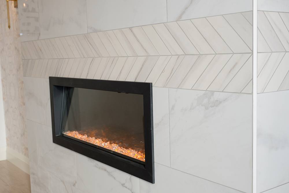 A chic electric fireplace in a wall of white marble tiles