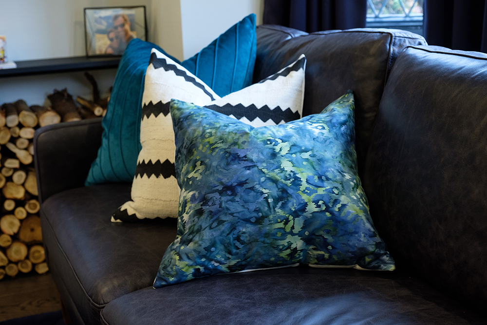 A dark-brown leather couch with blue and black-and-white throw pillows