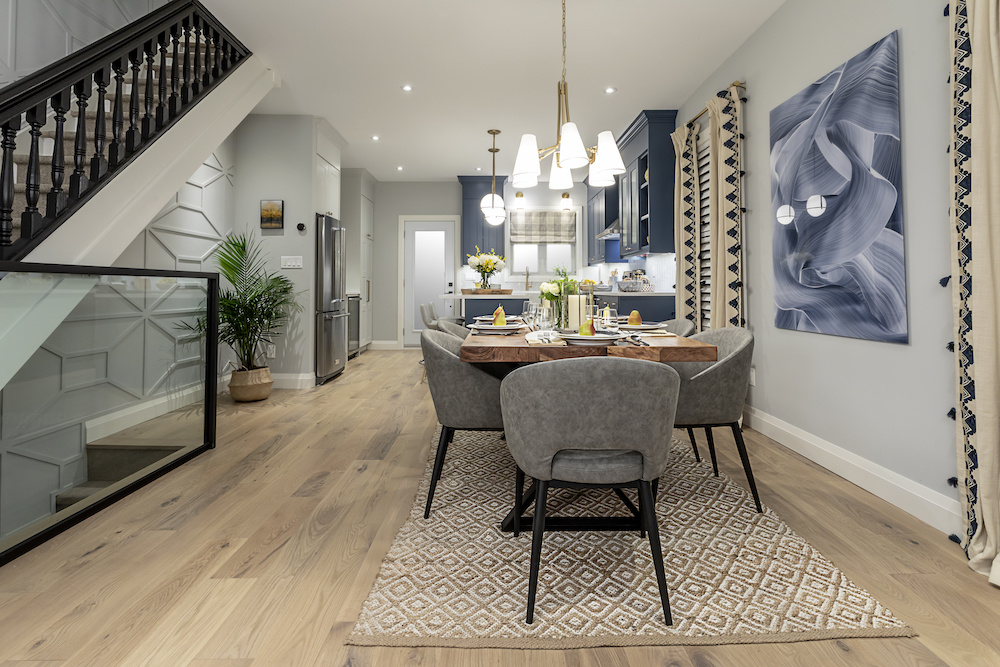 An open concept dining room with large wooden table and six grey upholstered chairs