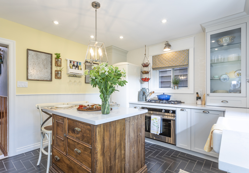 Newly renovated kitchen with wooden centre island, white countertops and a black herringbone tile floor