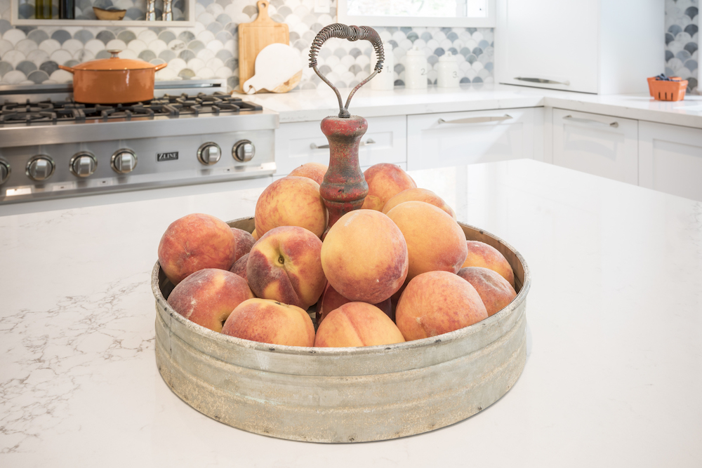 A bowl of peaches sits on a white quartz countertop in newly renovated kitchen