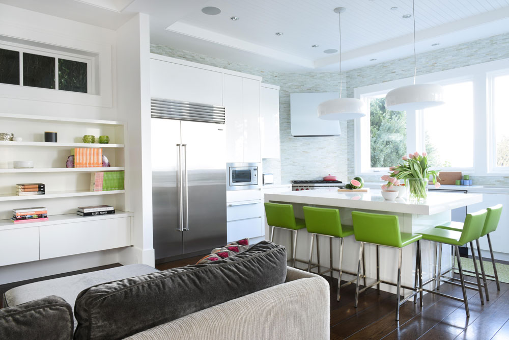 kitchen with island and green stools, stainless steel fridge and view to living room shelves