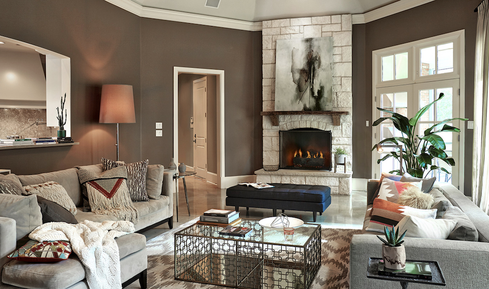 Beautiful living room with an open fireplace, two large grey couches, a chic metal coffee table, and BEHR Kindling N200-6 and Cotton Knit PPU7-11 painted on the walls