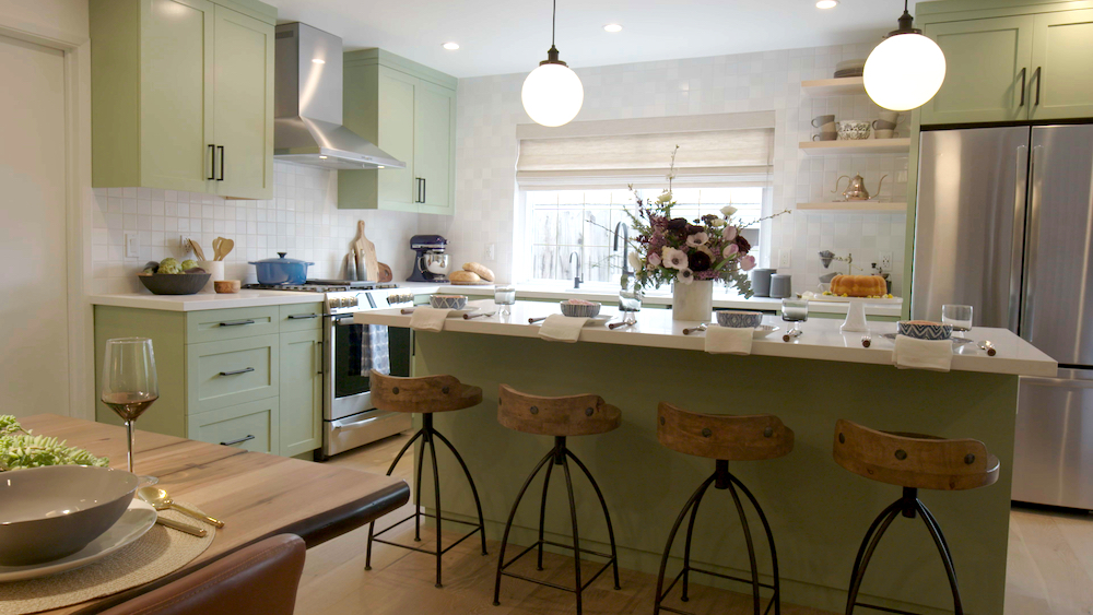 Cool modern kitchen with mint green cabinets, a kitchen island with two round pendant and four wood bar stools