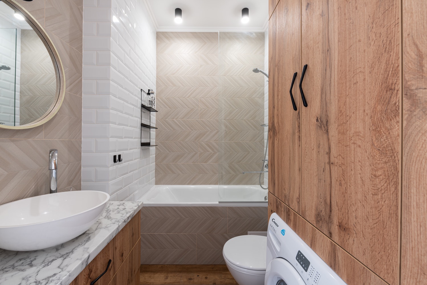 Bathroom with wood cabinets, washer, marble countertop and white subway tile