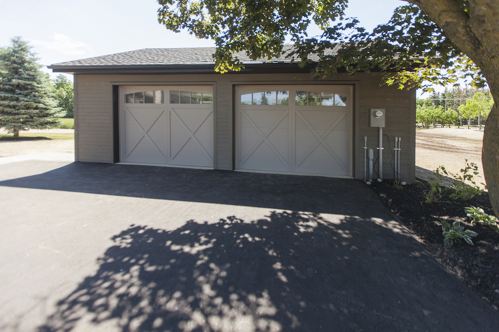 Fully renovated two car garage with white doors and a new shingled roof