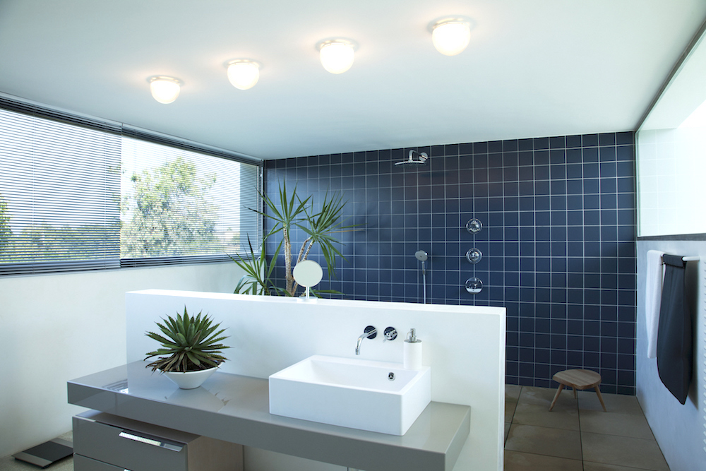 Blue tiled open shower in modern bathroom with white sink