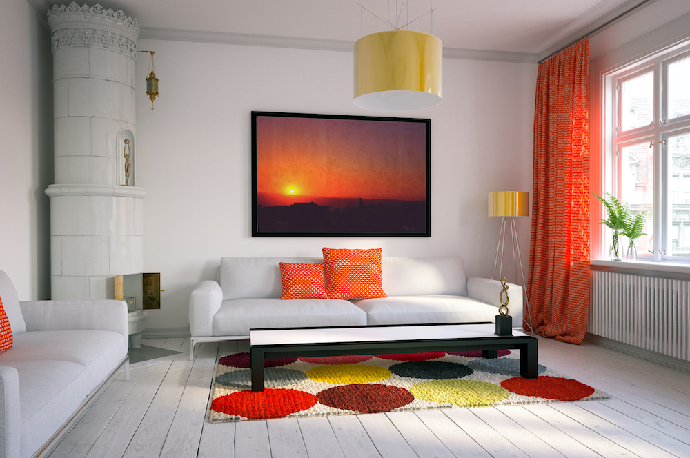 Cozy Scandinavian style interior of a living room with two large white couches, white floor boards, a black coffee table, corner white tiled fireplace, large sunset painting on a white wall, large yellow pendant lamp, and a yellow floor lamp in the right corner