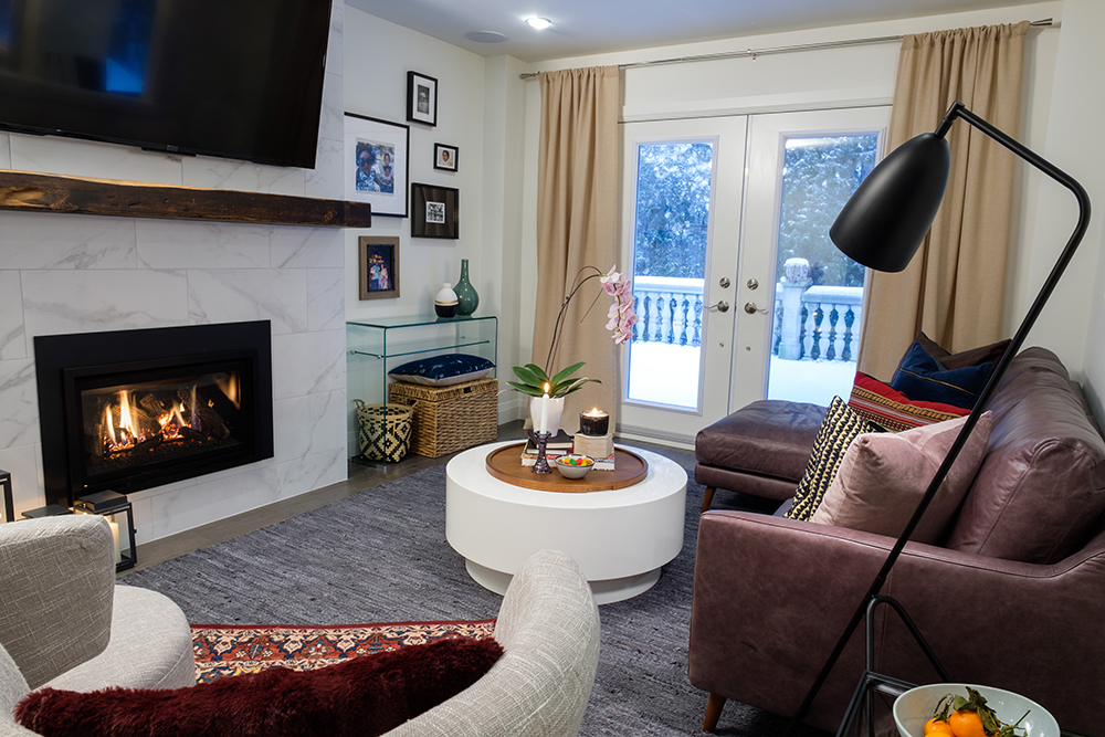 Chic family room with a brown leather couch, black floor lamp, gas fireplace and large TV
