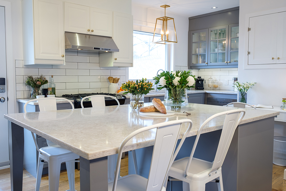 Chic modern kitchen with a centre island, metal chairs and white cabinets