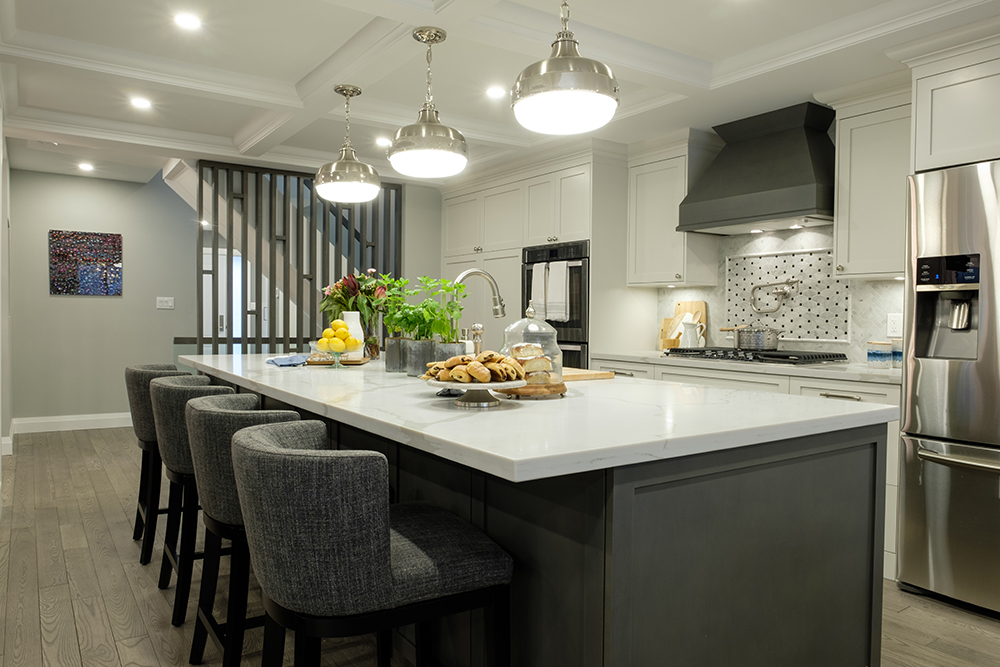 Large white centre island surrounded by plush grey bar stools in a modern kitchen