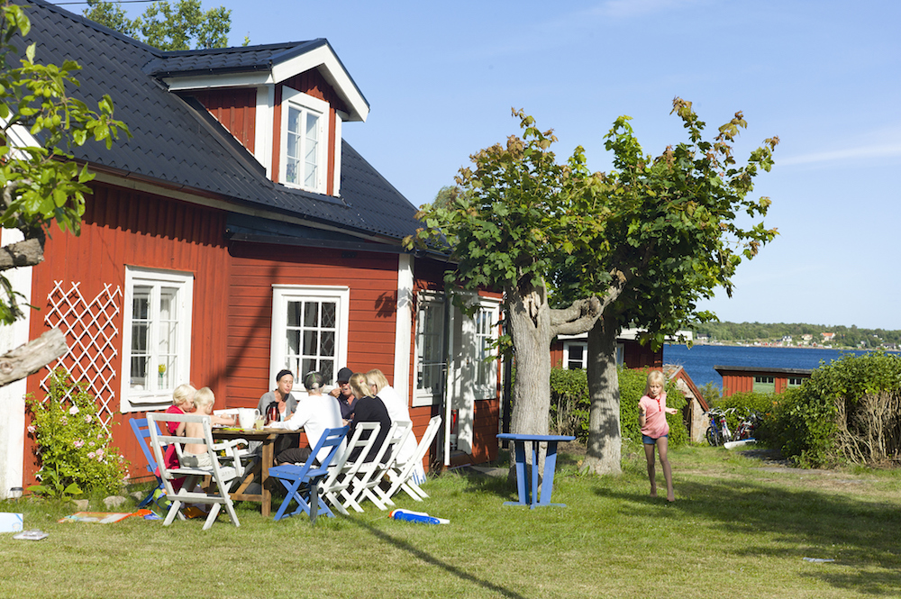 Family having a nice meal in front of their red summer cottage