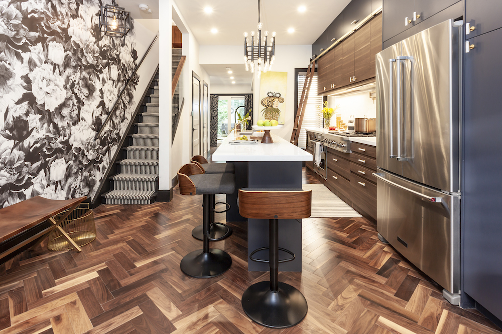 Chic kitchen with dark wood herringbone floors, large stainless steel appliances and navy blue kitchen island